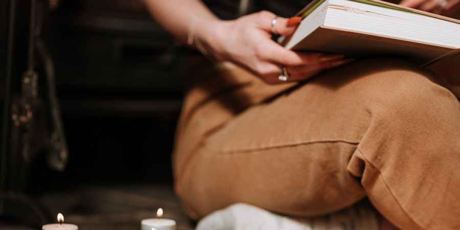 Woman Reading Old Book Near Burning Candles During Ritual